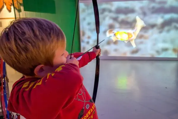 Young boy shooting with bow and arrow
