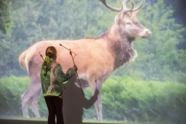Girl stands and evaluates her target shots with a bow and arrow.