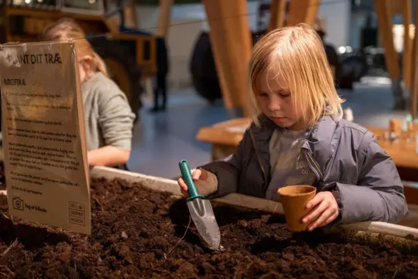 A child is planting an acorn at the Green Museum.